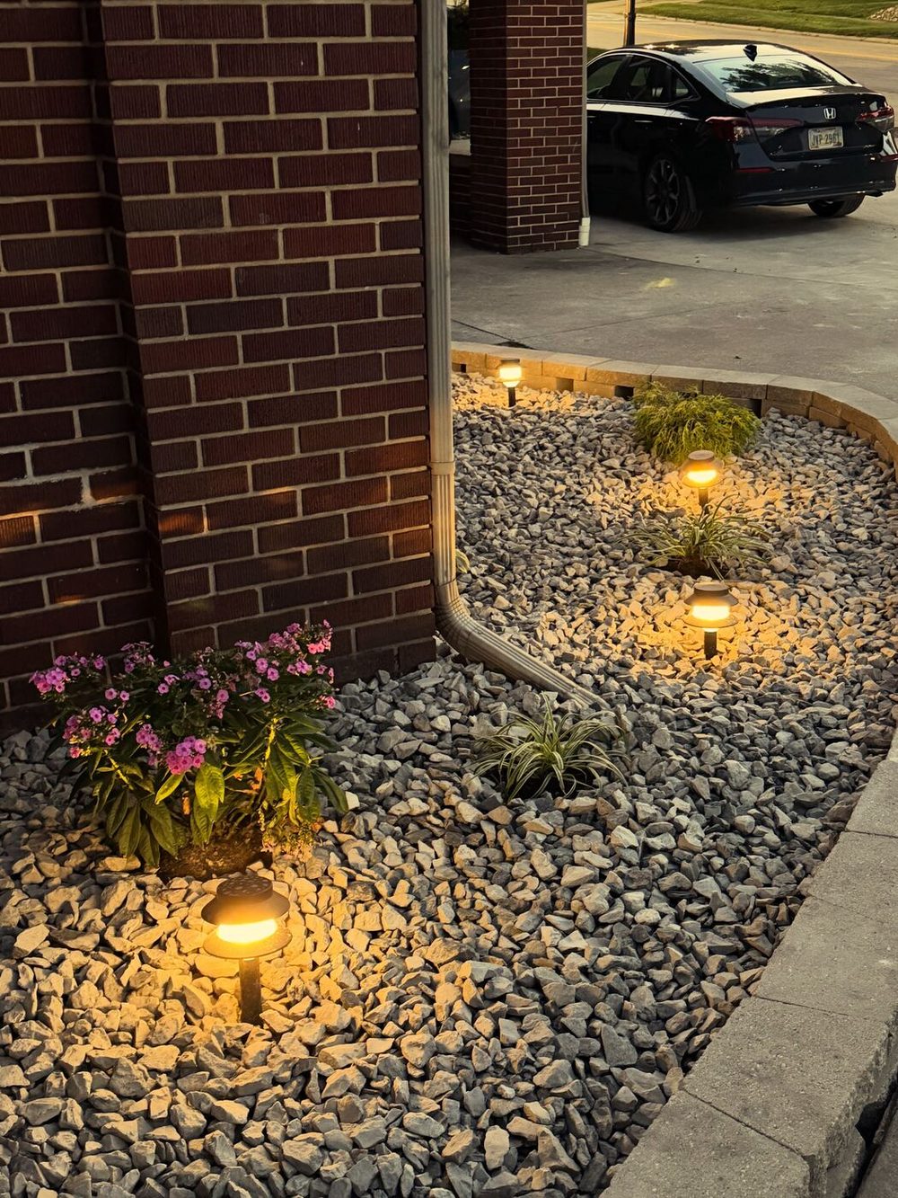 Path lights glowing in a rock bed along a driveway