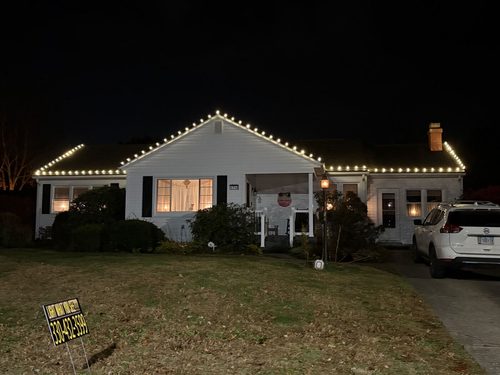 Warm white holiday lighting along a ranch home's roofline