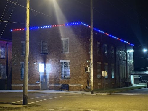 Permanent red, white and blue trim lighting on a commercial brick building roofline