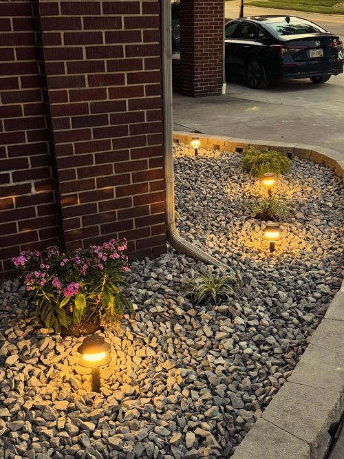 Landscape lighting and rock bed install along a home foundation and driveway