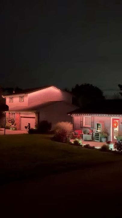 A home's rooflines and porch lit with permanent lighting at night